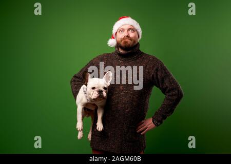 Male in santa hat avec bulldog sur fond vert en studio vide Banque D'Images