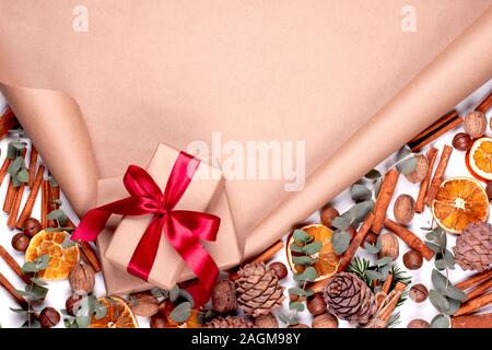 Cadeaux avec ruban rouge sur le défilement du papier motif entouré par des écrous, des cônes, des oranges, des eucalyptus, des bâtons de cannelle Banque D'Images