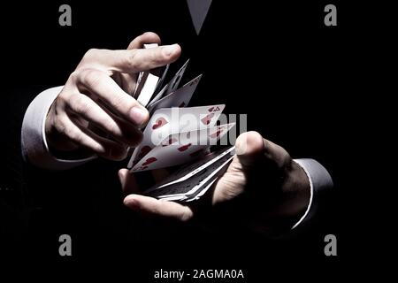 Magicien agitant les cartes d'une manière fraîche sous le projecteur Banque D'Images