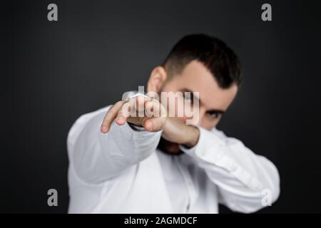 Jeune homme à la main points vous sur fond noir. Se concentrer sur la main. homme pointant à l'avant Banque D'Images