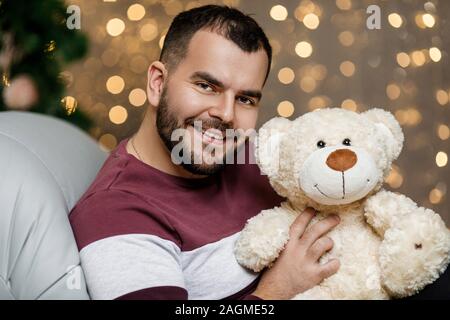 Homme barbu souriant holding ours sur fond de lumières de Noël Banque D'Images