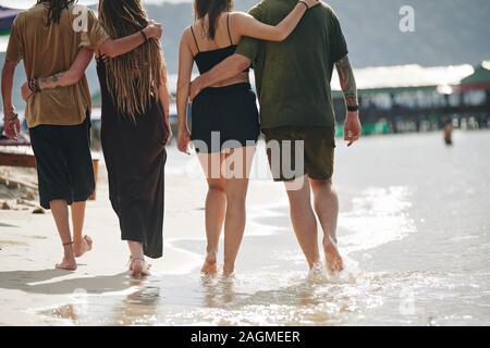 Portrait de deux accolades des couples à marcher le long de la mer de sable aux beaux jours Banque D'Images