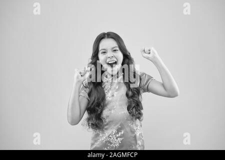 Shes un vrai gagnant. Petite fille crier et faire le geste gagnant sur fond rose. Heureux gagnant de petits gestes active dans un style chinois. Heureux vainqueur célébrant la victoire ou la réussite. Banque D'Images