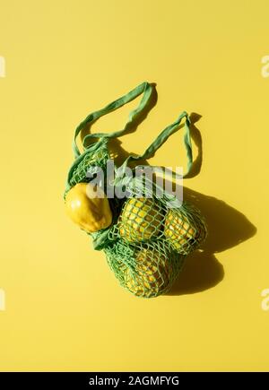 Quince fruits dans un sac de toile verte sur fond jaune. Télévision jeter fruits d'automne en sac réutilisable. Une alimentation saine et respectueuse de l'environnement de magasinage. Banque D'Images