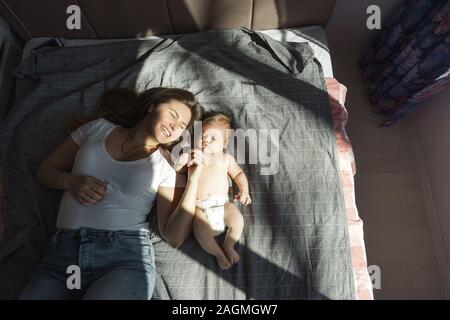 Mère et son fils nouveau-né était étendue sur le lit dans les rayons du soleil Banque D'Images