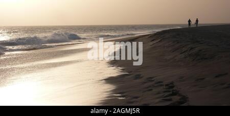 Un couple bénéficiant d'un coucher du soleil à pied sur une plage isolée au Cap Vert Banque D'Images