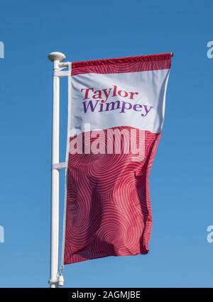 Westergate, West Sussex, UK, 06 octobre 2019. Taylor Wimpey Drapeau Rouge voletant dans la brise à l'entrée de leur nouveau développement des haies. Banque D'Images