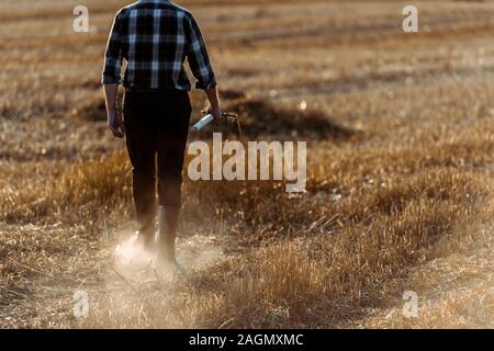 Portrait of senior man holding rake en marchant champ de blé Banque D'Images