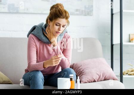 Femme malade et attrayant avec foulard gris à thermomètre à Banque D'Images