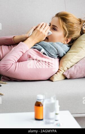 Portrait de femme malade et attrayant avec foulard gris d'éternuements et de l'utilisation de serviette Banque D'Images