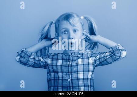 Funny Portrait of young girl making faces en face de la caméra. Enfant tenant tirant faisant glisser les oreilles. Kid : exprimer des sentiments. April fool day concept. Ton Banque D'Images