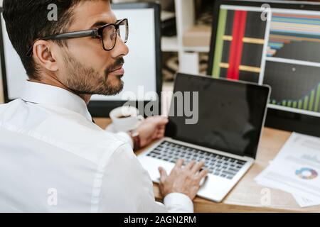 Focus sélectif de bi-raciale assis près de trader et d'ordinateurs portables Banque D'Images