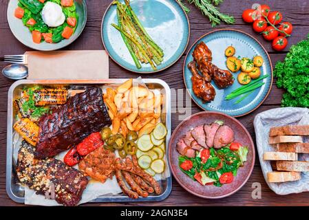 Vue de dessus du snack-combo la composition avec des côtes levées, poulet, les quartiers de pommes de terre, saucisses, le maïs et le piment jalapeno, salade de saumon, asperges, pain. Selective Banque D'Images