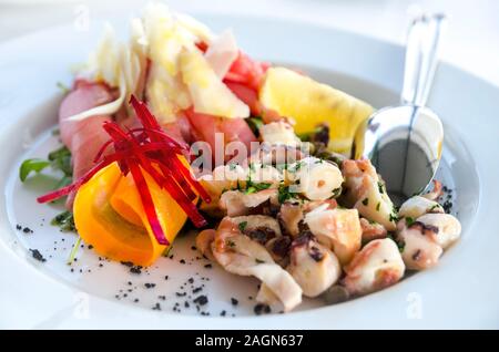 Une salade de fruits de mer servi en gros plan de la plaque blanche. Le poulpe et poisson salade de thon au citron apéritif sur la table de restaurant. Recette de cuisine méditerranéenne. Luxur Banque D'Images