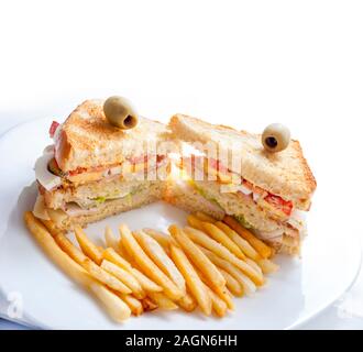 Gros-plan des sandwichs du club avec poulet, œufs, salade, pain grillé et frites servis sur une plaque blanche. Restaurant-snack-déjeuner sain isolé o Banque D'Images