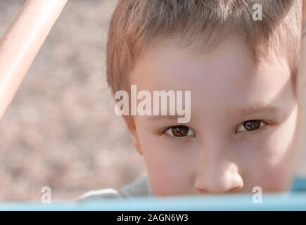 Portrait de jeune garçon à la recherche de l'appareil photo sur l'aire de jeux pour enfants. L'enfant s'amuser sur l'aire de jeux. Enfant jouant sur une aire de jeux pour enfants Banque D'Images