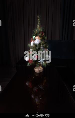 Beau petit et décoré l'arbre de Noël et beaucoup de cadeaux à la maison avec un fond sombre Banque D'Images