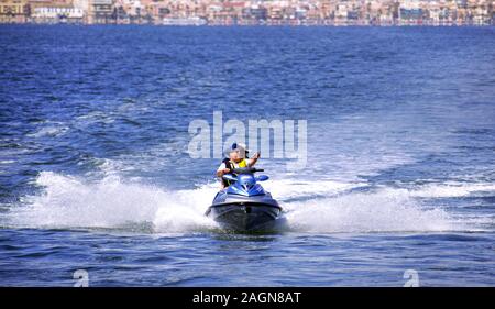 La manga, Murcia, Espagne, le 2 août 2010 : deux hommes touristiques bénéficiant d''un scooter ride sur une chaude après-midi d'été dans les eaux peu profondes de la plage Banque D'Images