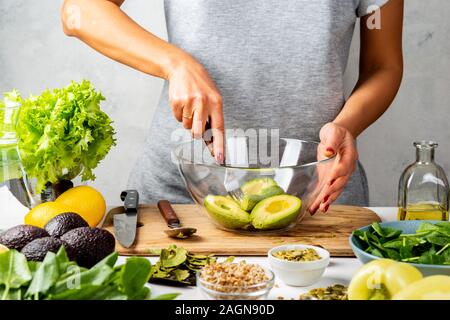 Femme écraser l'avocat avec une fourchette, la cuisine le guacamole dans un bol en verre. Une alimentation saine notion Banque D'Images