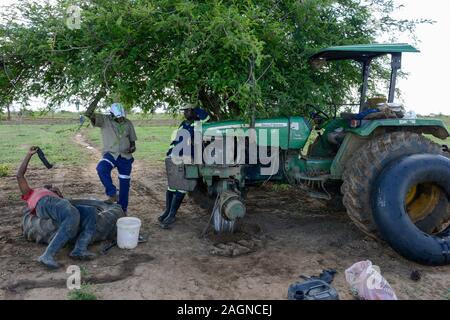 La ZAMBIE, Mazabuka, moyen agriculteur avec tracteur John Deere, bouchant un tube d'un pneu à plat sur le terrain Banque D'Images
