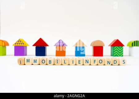 Bloc en bois avec des lettres pour dire 'Immobilienfonds' (allemand pour les fonds immobiliers) en face de maisons jouet coloré Banque D'Images