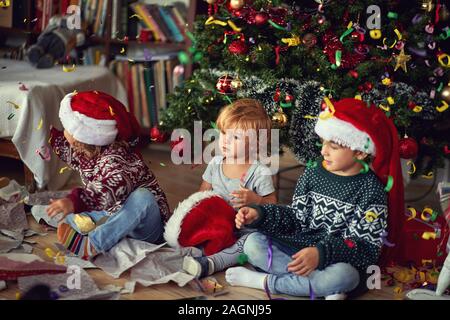 Heureux les enfants qui jouent par arbre le matin de Noël Banque D'Images