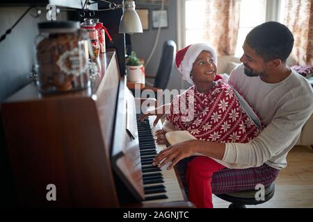 Jeune père avec ma petite fille à Noël jouer de la musique au piano. Banque D'Images