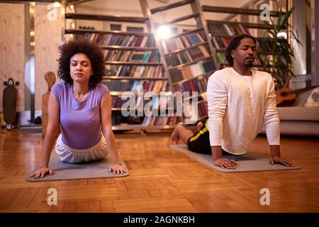 La femme et l'homme pratiquant le yoga piscine Banque D'Images