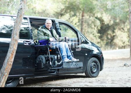 Les personnes handicapées en fauteuil roulant sur l'homme debout sur la voiture ascenseur Banque D'Images