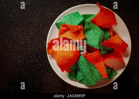 Vue de dessus de croustilles au rouge et vert sur une plaque Banque D'Images