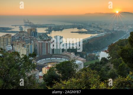 Coucher de soleil sur Malaga sur la Costa del sol espagnole avec vue panoramique sur la ville, le port, les maisons, les arbres, le taureau avec lumière de rue Banque D'Images