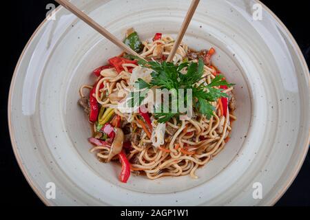 Pad Thaï légumes végétarien nouilles Udon dans un fond sombre, vue du dessus. La nourriture végétarienne au style asiatique. Copy space Banque D'Images