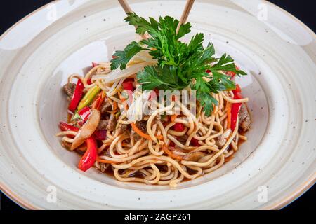 Pad Thaï légumes végétarien nouilles Udon dans un fond sombre, vue du dessus. La nourriture végétarienne au style asiatique. Copy space Banque D'Images