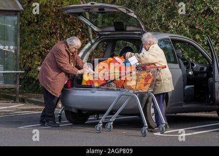 Les femmes âgées déchargeant leurs achats dans leur voiture dans un parking de supermarché, Angleterre, Royaume-Uni Banque D'Images