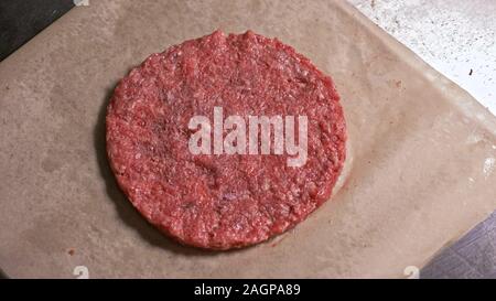 Faire cuire les médaillons de viande fait pour les hamburgers. Chef en noir gants alimentaire rend escalope. Les escalopes sont de niveau dans l'anneau d'acier dans un même médaillon. Banque D'Images