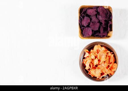 Carottes séchées et croustilles de betteraves dans un bol en bois sur une base en béton blanc. Aliments naturels biologiques. Copier l'espace. Banque D'Images