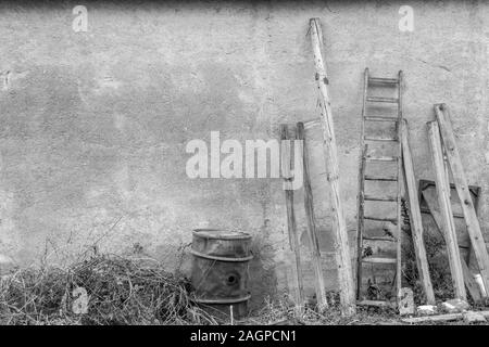 Divers outils et équipements agricoles faire jeter contre un mur du bâtiment hangar agricole. Banque D'Images