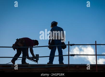 Les travailleurs de la construction d'ossature sur la toiture du bâtiment. Banque D'Images
