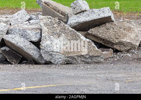 Des fragments d'asphalte et de béton brisées sont empilés sur le sol dans un parking. Les fragments de pierre ont été déterrés et arrachés du lot. Banque D'Images