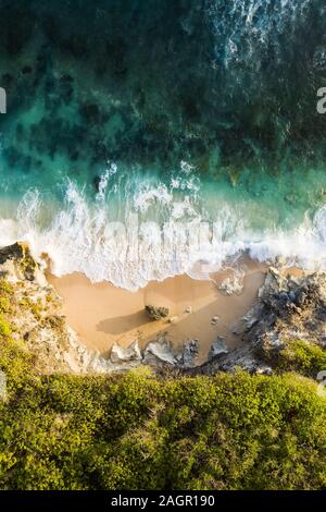 Vue de dessus, superbe vue aérienne d'une côte rocheuse avec une belle plage baignée par une mer agitée pendant le coucher du soleil, Plage Nyang Nyang, Bali, Indonésie. Banque D'Images