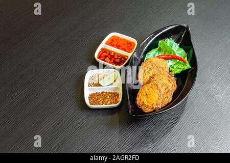 Gâteau de poisson frit épicé, Tod Mun (Pla), un apéritif traditionnel de la Thaïlande est à base de pâte de poisson, de temps les haricots, pâte de curry rouge et partie lime kaffir Banque D'Images