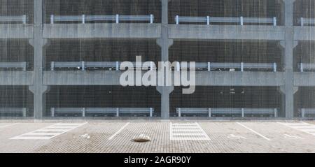 Plancher ouvert de parking multi-niveaux protégés par le vaste arrière-plan panoramique de maille en acier Banque D'Images