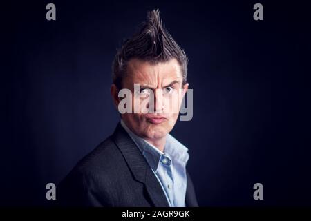 Homme Handsone avec port mohawk costume dans l'avant du fond noir. Banque D'Images