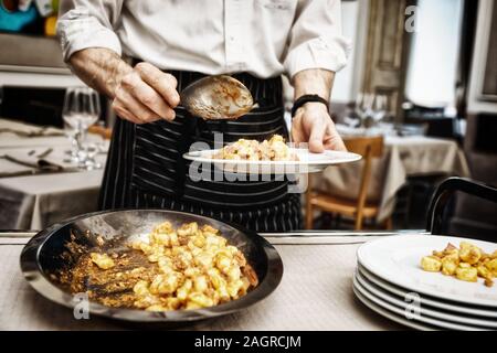 Chef, c'est mettre la viande avec gnocchi en plaques, tonique libre Banque D'Images