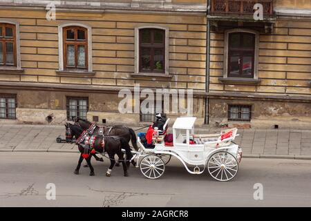 Transport de chevaux dans la rue de la vieille ville de Cracovie, Pologne. Deux chevaux dans le magnifique vieux coach, animation pour les touristes en excursion. Banque D'Images