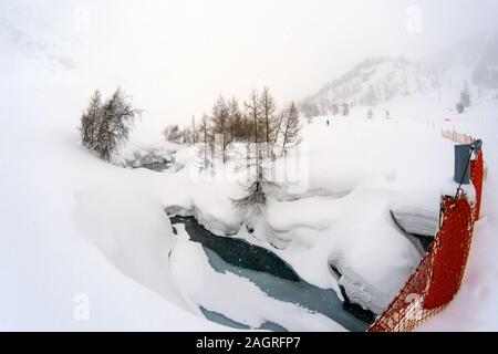 Frozen River à Isère ville Fornet à Alpes Françaises. Les arbres sans feuilles et neige en hiver extrême condition. Bande de sécurité pour protéger les gens. Banque D'Images