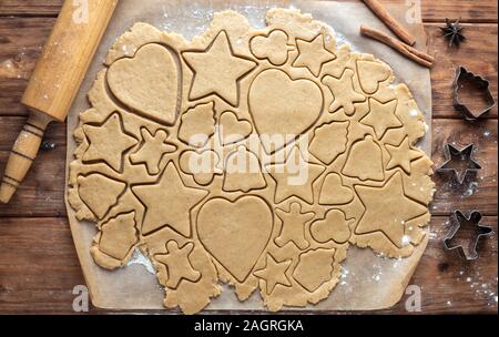 La pâte à biscuits au gingembre avec des figures découpées sur un fond de bois. Vue de dessus Banque D'Images