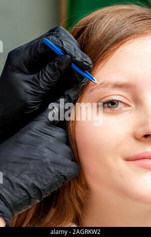 Les mains dans des gants noirs à plumer des sourcils avec des brucelles, Close up Banque D'Images