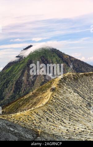 Vue imprenable sur le volcan Ijen avec montagnes complexe entouré par les nuages pendant le lever du soleil. Banque D'Images