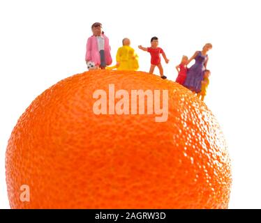 Figurines miniatures,maman,les mères enfants,enfants,debout sur un satsuma orange sur un fond blanc. Banque D'Images